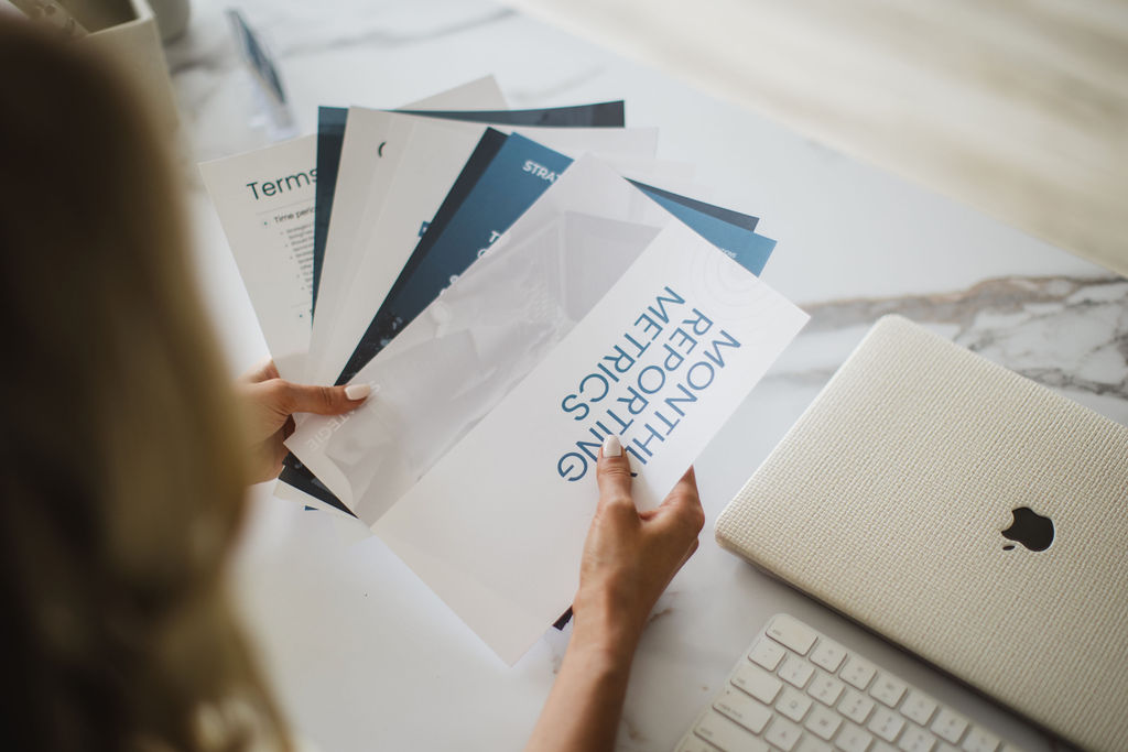 Person reviewing printed email marketing reports and monthly reporting metrics.