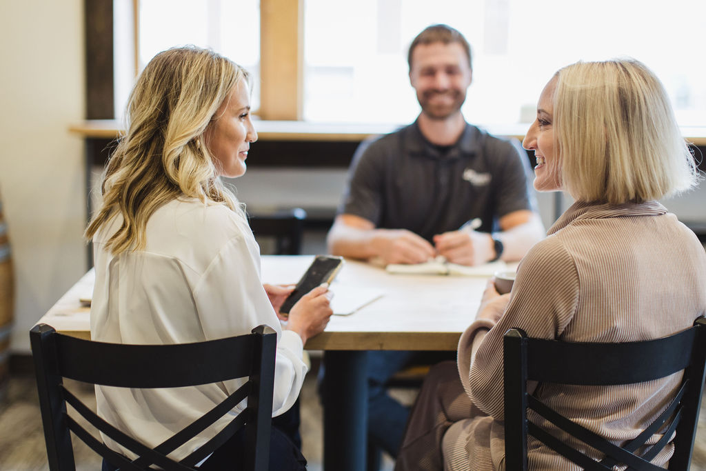 Two marketing professionals consulting with a client during a marketing strategy discussion at a table.