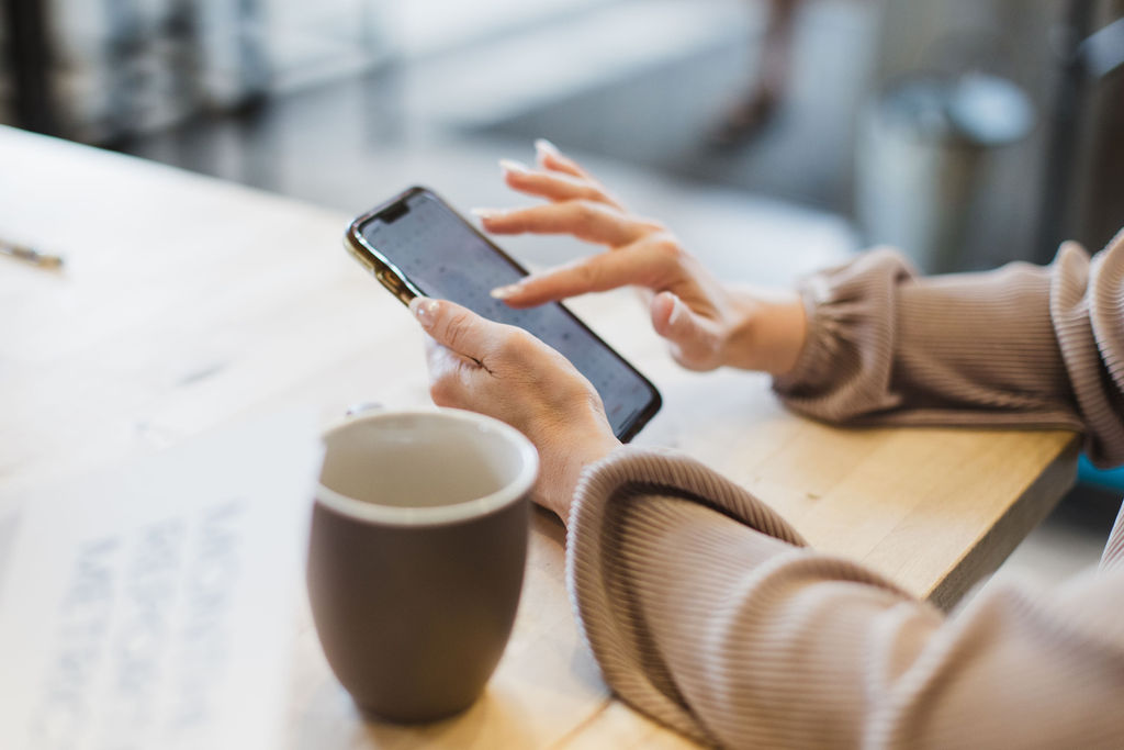 Hands holding a phone scrolling through social media.