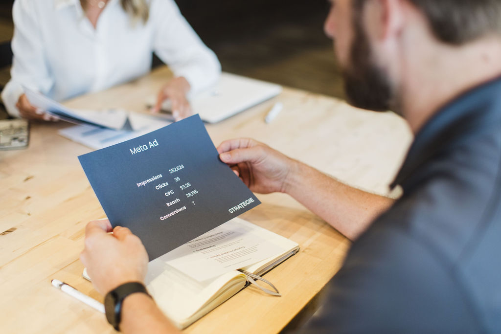 Person holding printed social media ad performance insights and breakdown.