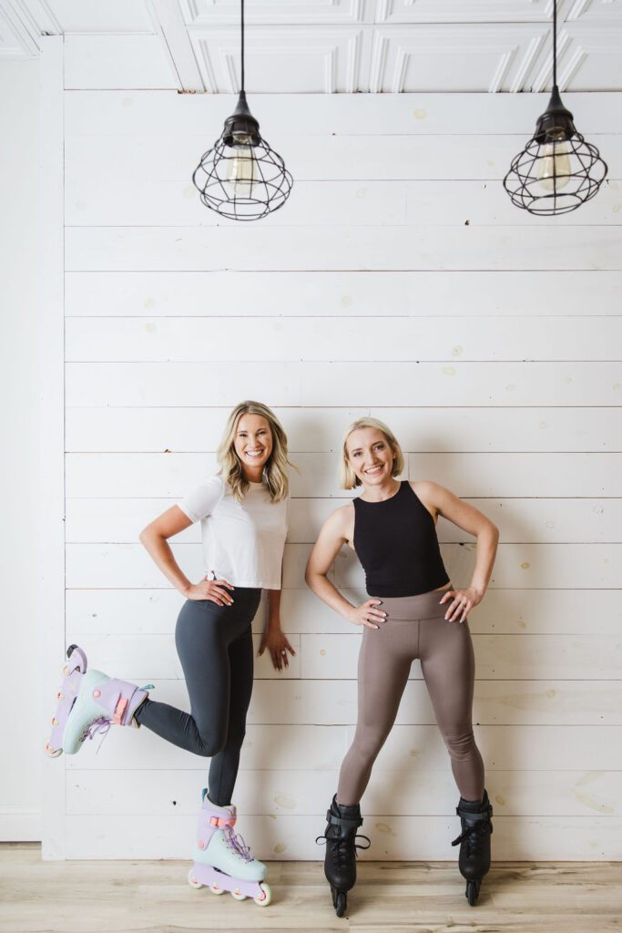 Two women wearing rollerblades standing together.