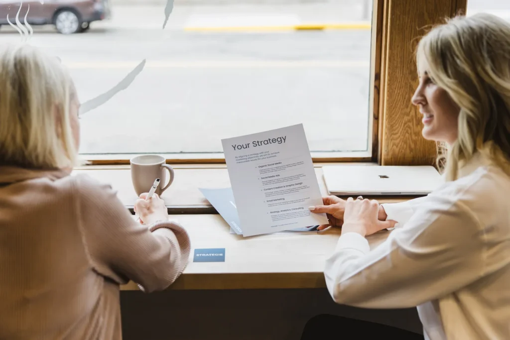 Two women review a social media strategy in a cafe.